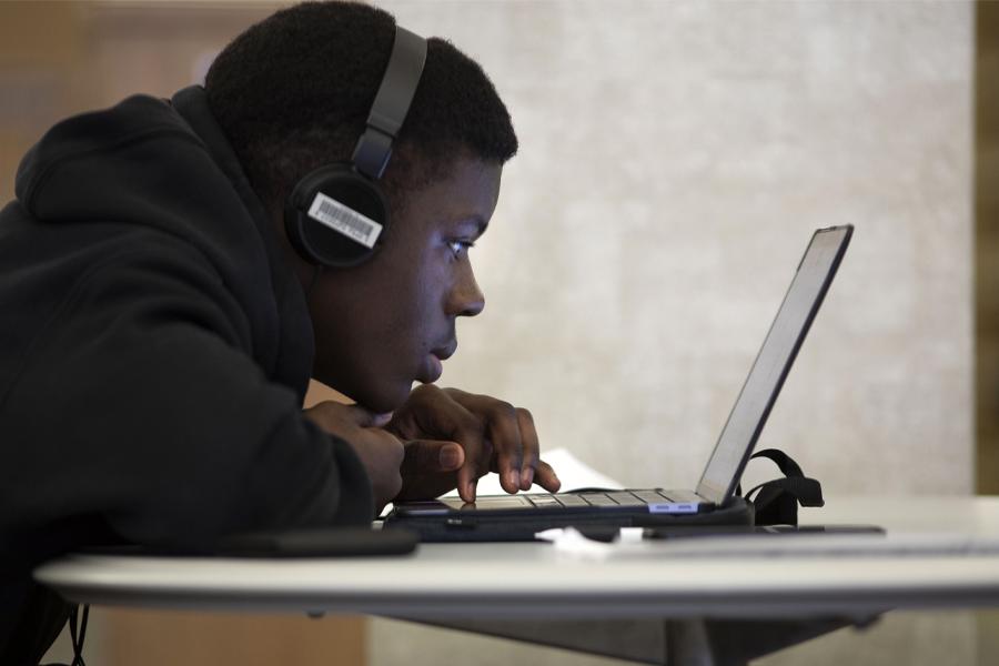 一名学生戴着耳机在笔记本电脑上学习.