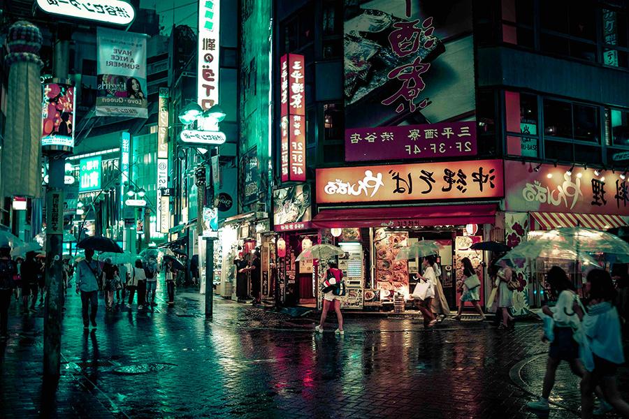 晚上，人们走在日本东京的街道上，街道上的彩色标志亮起.
