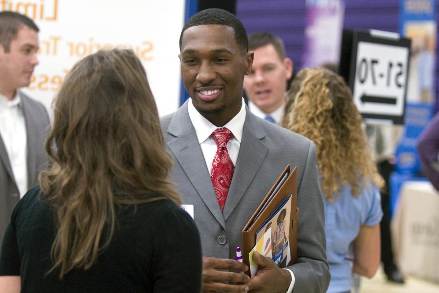 一个年轻的学生穿着西装打着领带在招聘会上交游.