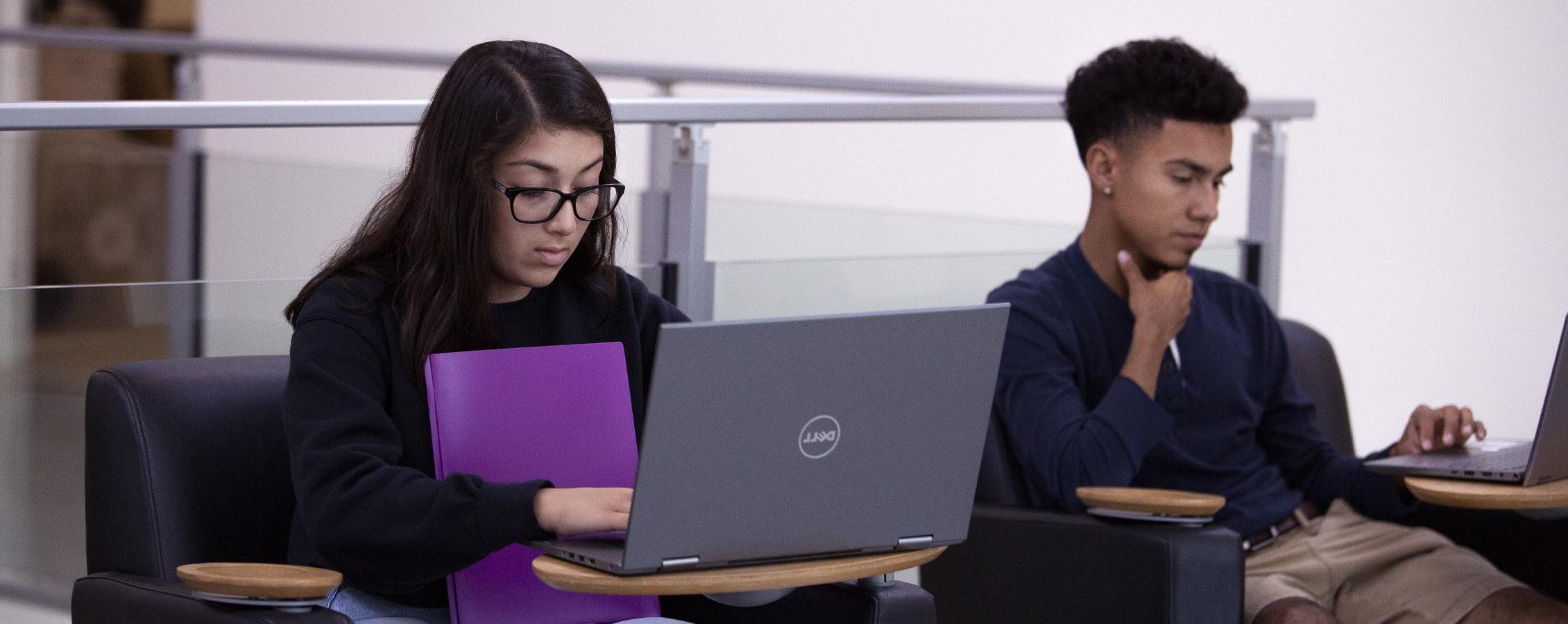 两名学生在会议室用笔记本电脑工作.