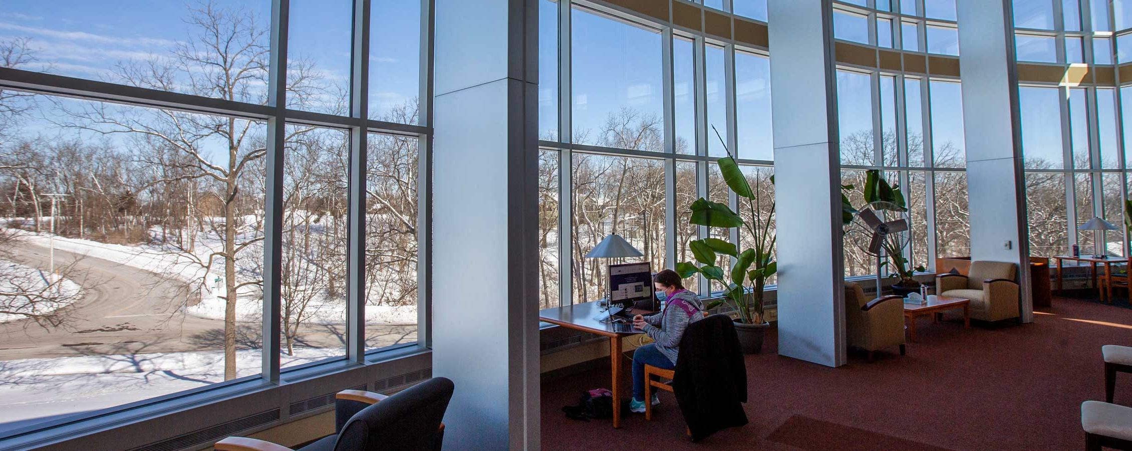 A student sits in front of the large windows in the Lenox Library on the 欧洲杯投注 Rock County campus.