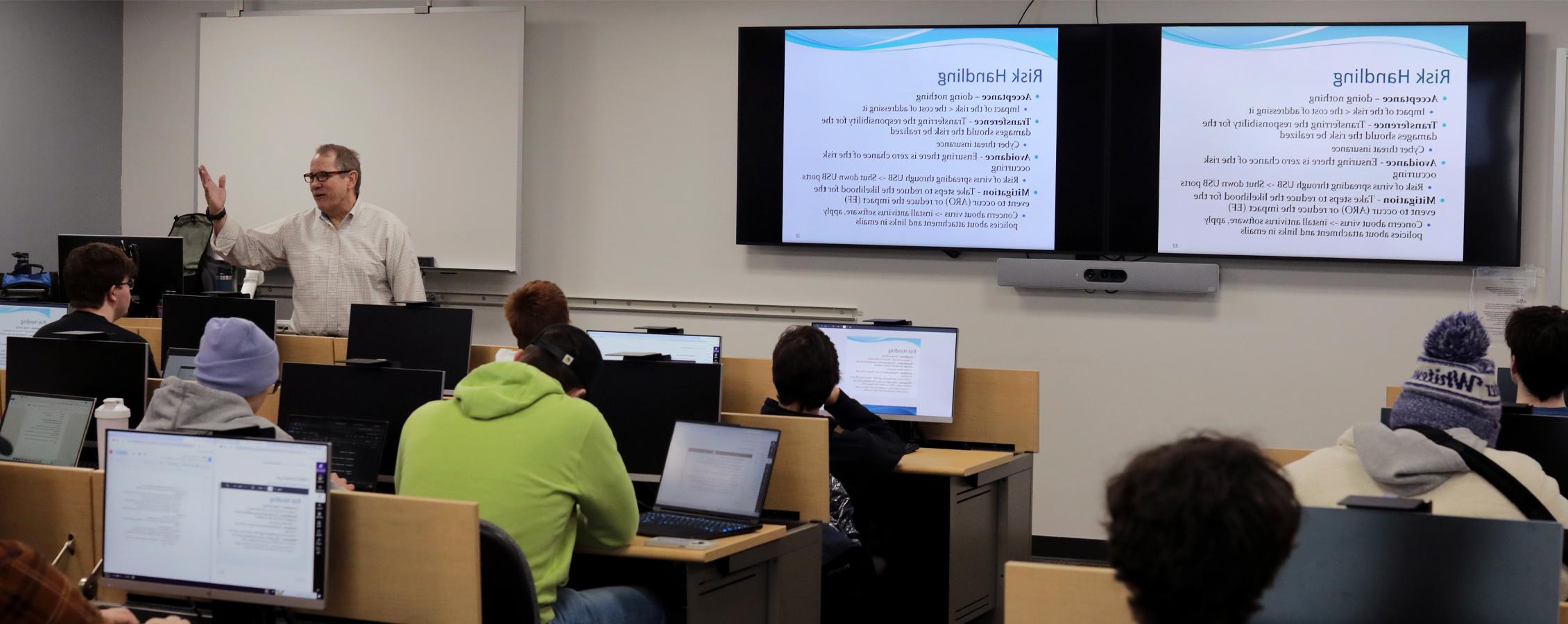 A faculty member speaks in front of a Cyber 101 class.