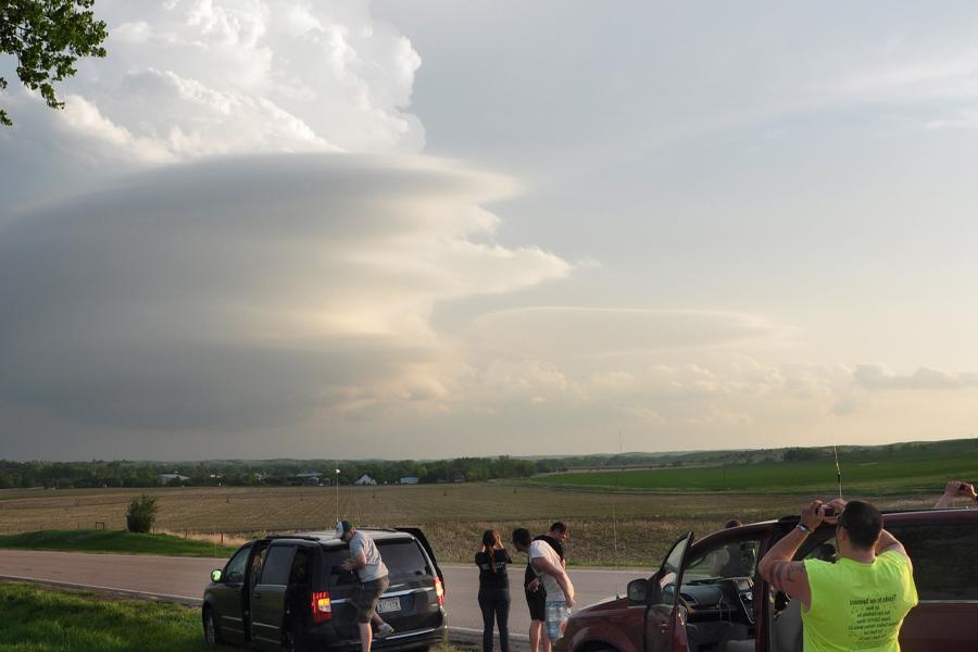 Students take pictures of a storm rolling in over a field.