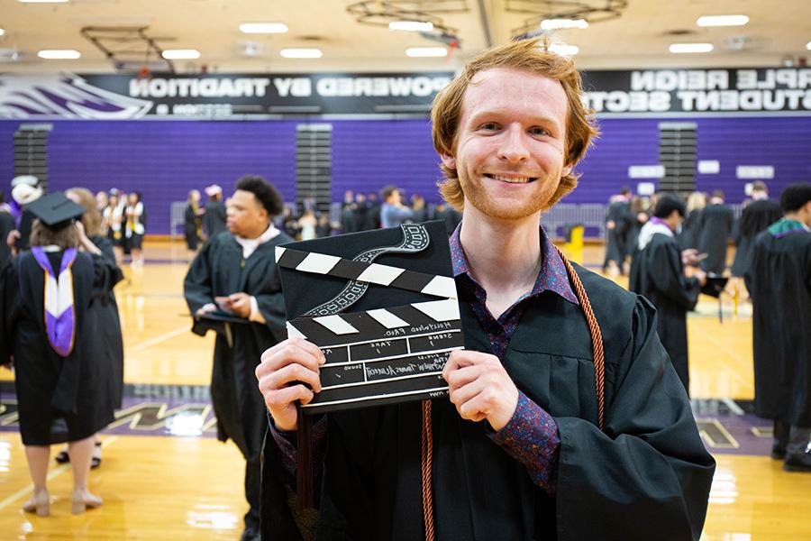 Matthew Albrecht at graduation shows his cap decorated like a clapperboard.
