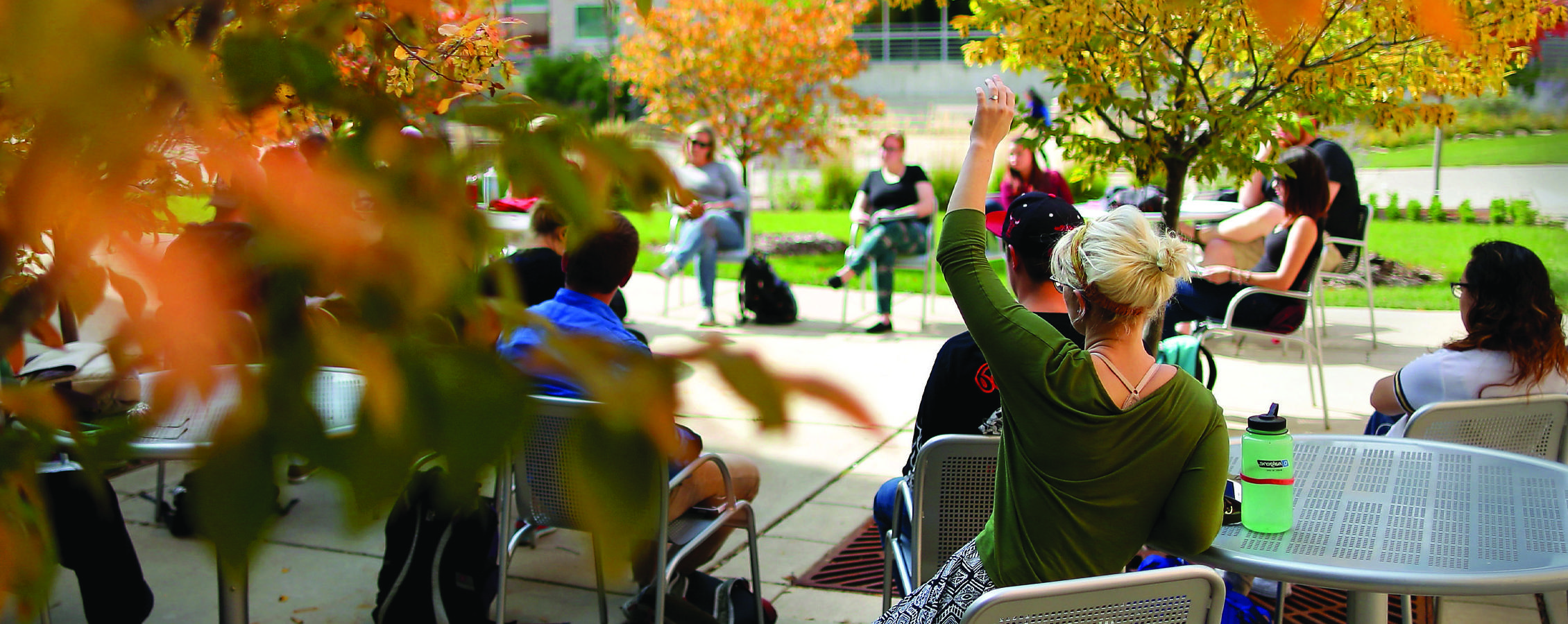 A class is held outside amidst fall leaves.