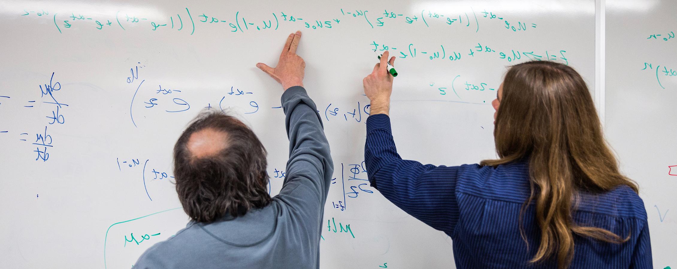 数学学生和教师在白板上工作