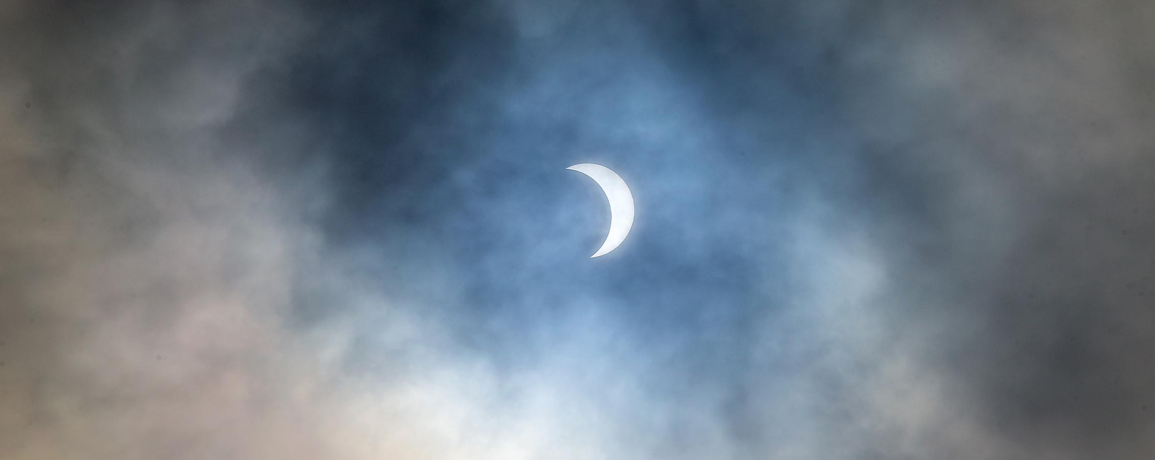 A solar eclipse surrounded by clouds.
