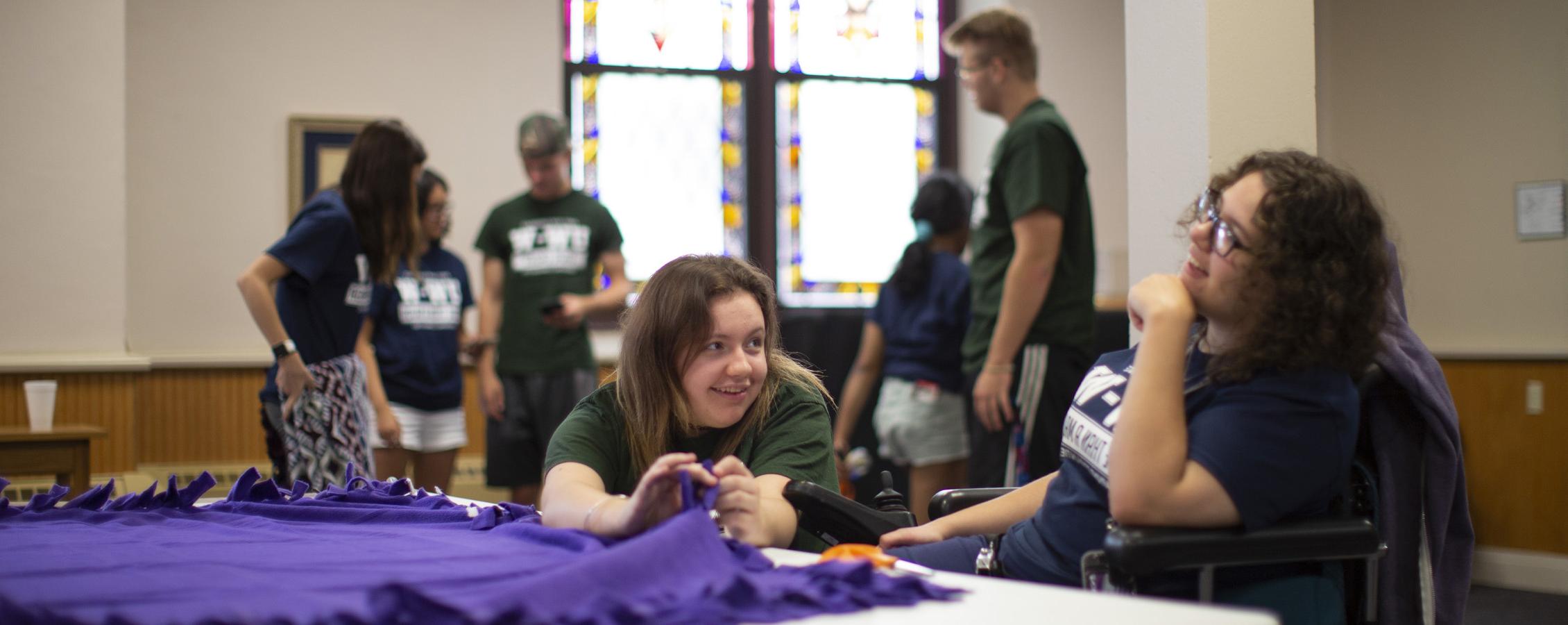 Two students make a purple blanket as they participate in community events.
