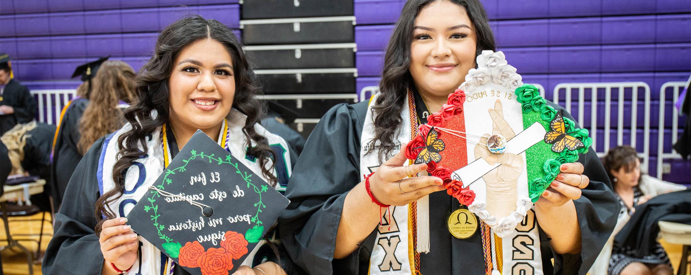 Two Spanish majors at graduation show their decorated caps.