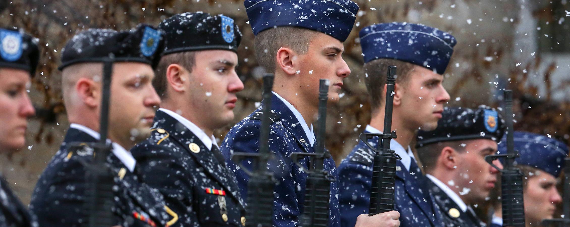 在下雪的时候，老兵们拿着步枪站在那里.