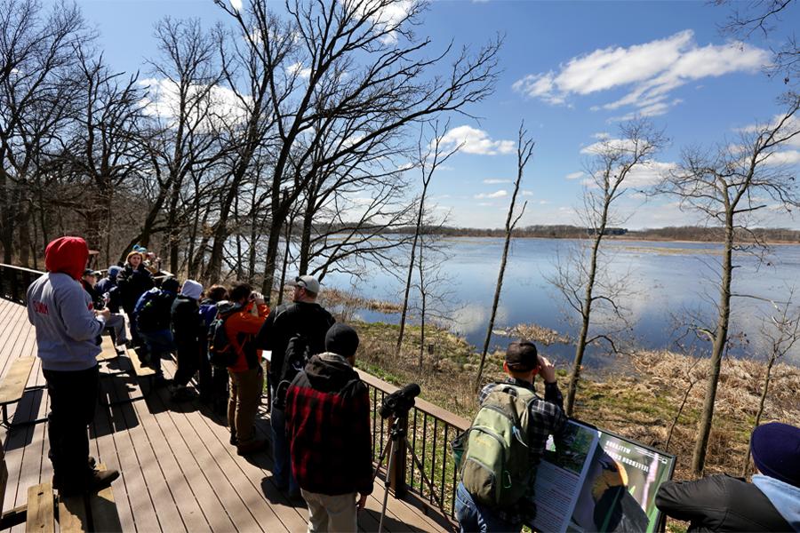 Biology majors stand on a deck overlooking a body of water.