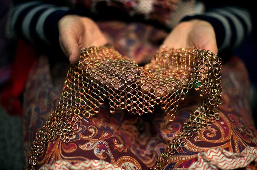 Two hands hold a large, looped, metal necklace.