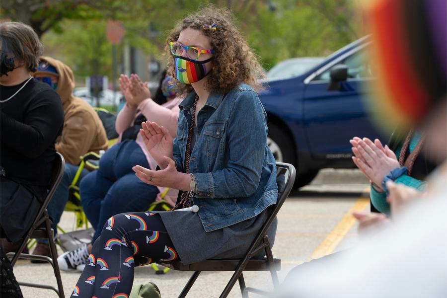 A student sits in a chair outside during the Rainbow Celebration of Excellence event.