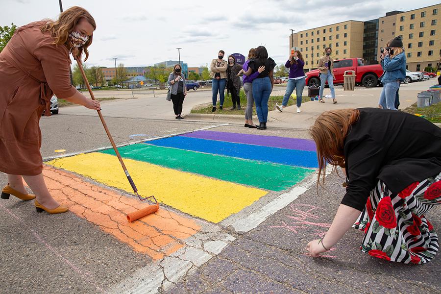 Ashley Barnes-Gilbert paints rainbow colors in a crosswalk on Warhawk Drive.